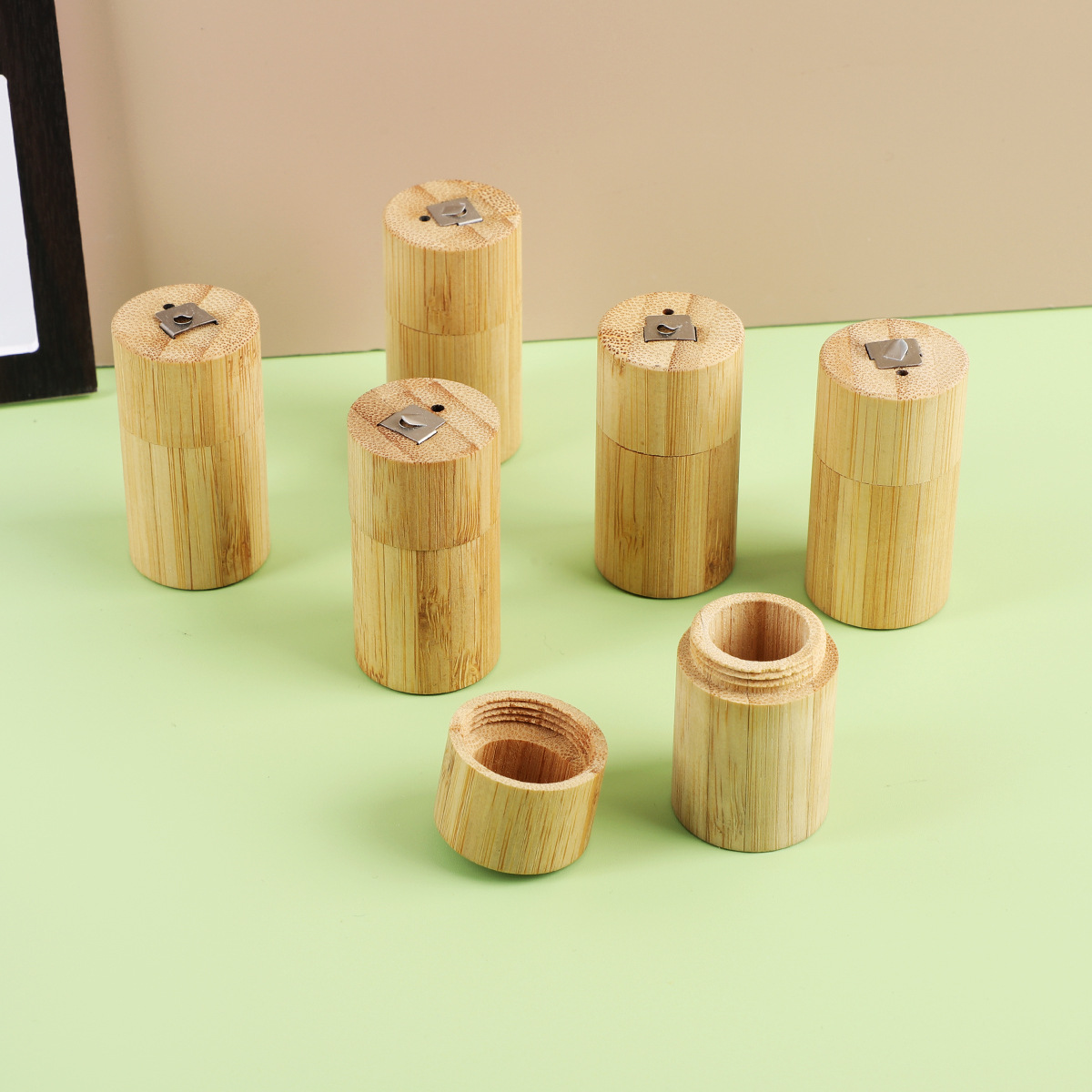 Light brown bamboo cylindrical floss tubes with metal clasps featuring a portable biodegradable case design.