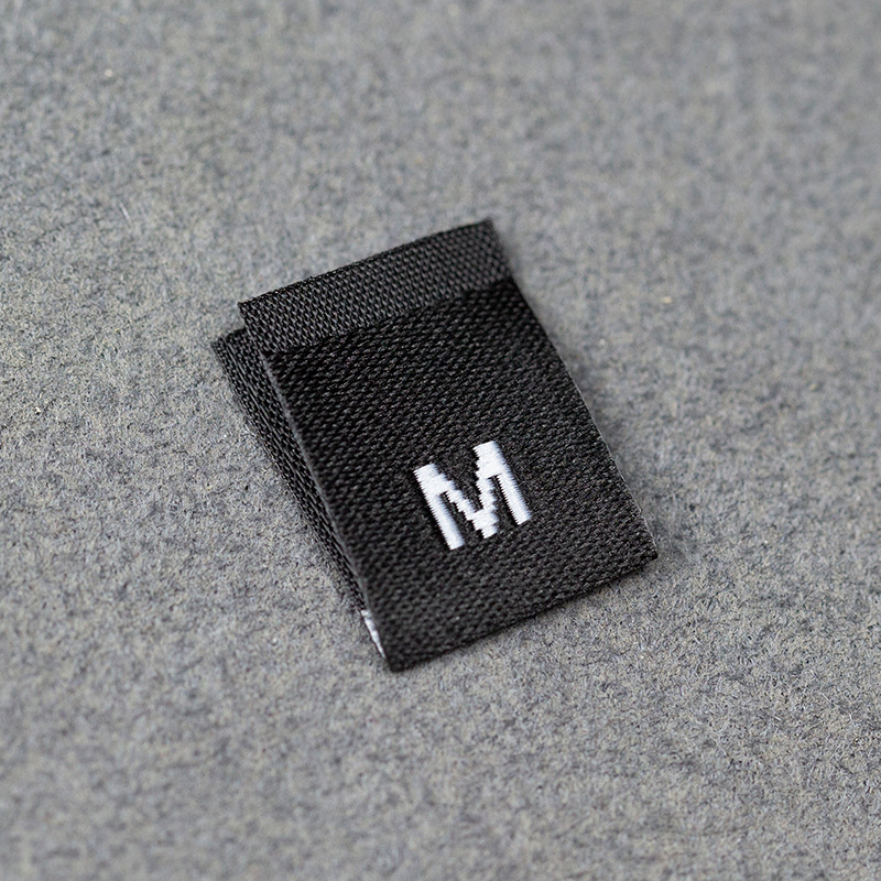 En stock Etiqueta de tamaño de alta densidad en blanco y negro Etiqueta de tamaño universal Etiqueta de código de letra inglesa Pantalones Etiqueta de código de cuello de camiseta