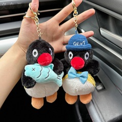 ぼんやりと萌えたペンギンのぬいぐるみが魚を抱いています。