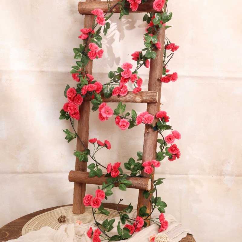 Simulación de flores falsas rosas de caña colgando la pared tubería de drenaje envuelta hoja verde que cubre la parte superior de la decoración de boda de plástico