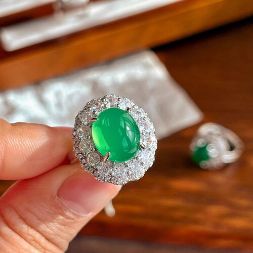 A natural light green jadeite egg face ring with a large, eye-catching green emerald, resembling jadeite, for women.