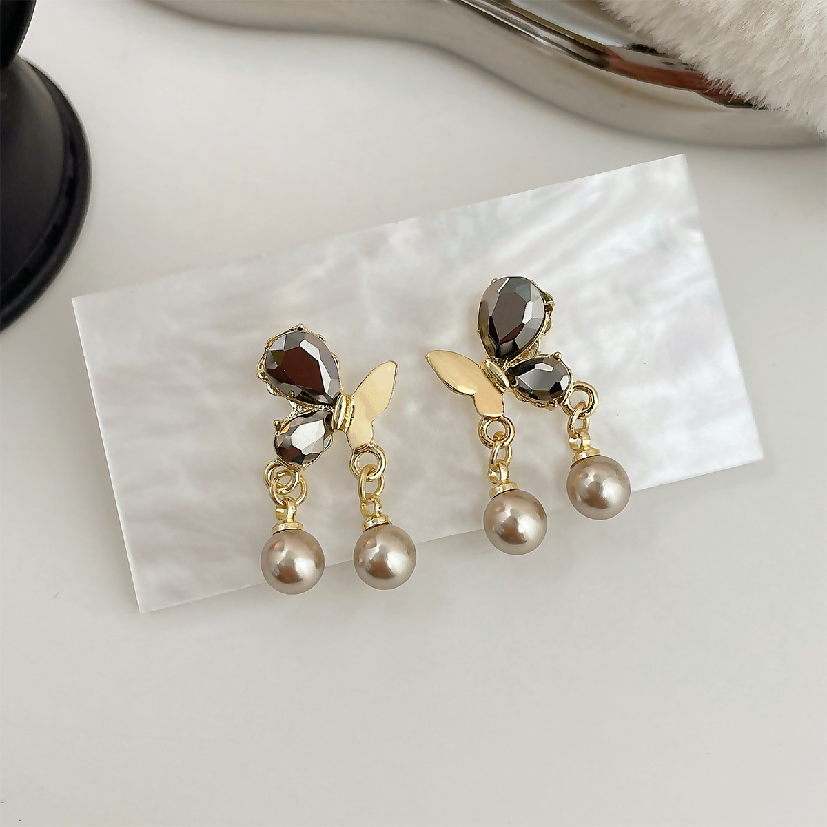 Pingente exclusivo de borboleta com pérola em preto e dourado, exclusivo para mulheres, com detalhe em prata, estilo luxuoso e discreto, ideal para o outono/inverno._voghion.com