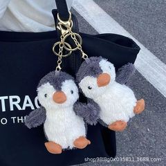 かわいい頬紅落花生のペンギンのキーホルダーにぬいぐるみペンギンのぬいぐるみカップルの小さなプレゼントのかばんが飾られている