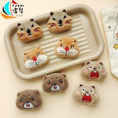 かわいい土番鼠の表情がぬいぐるみのブローチを包んでいます。