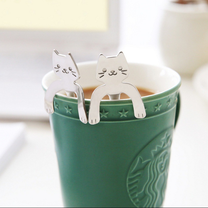 漫画の猫のマグカップの猫のスプーンは長い柄のスプーンのデザートをかき混ぜます。|undefined