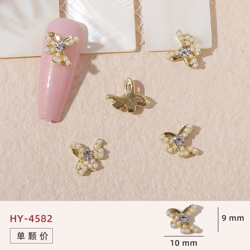 Uñas mariposa joyería nueva línea popular perla arco metal decoración de uñas pequeños accesorios de joyería al por mayor