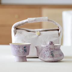 戸外携帯茶器セット1つのポット2杯の高颜値旅行茶器はお茶を入れて手でポットをつかむカップと収納袋を持っている