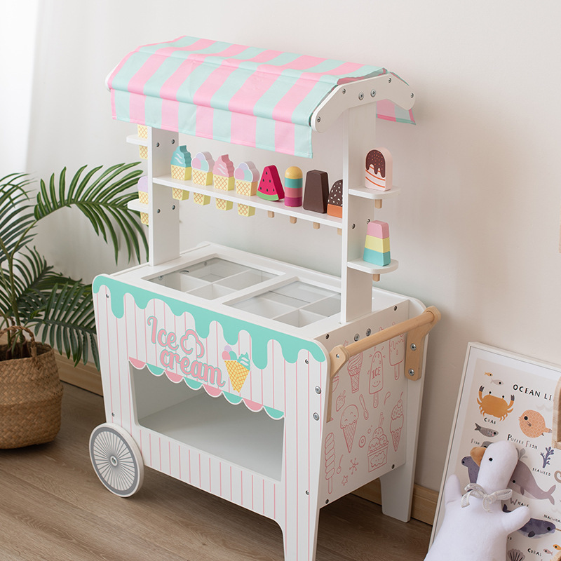 子供の木のおもちゃのままごとは白いアイスクリームの屋台のおもちゃの赤ちゃんの役をシミュレーションします。|undefined