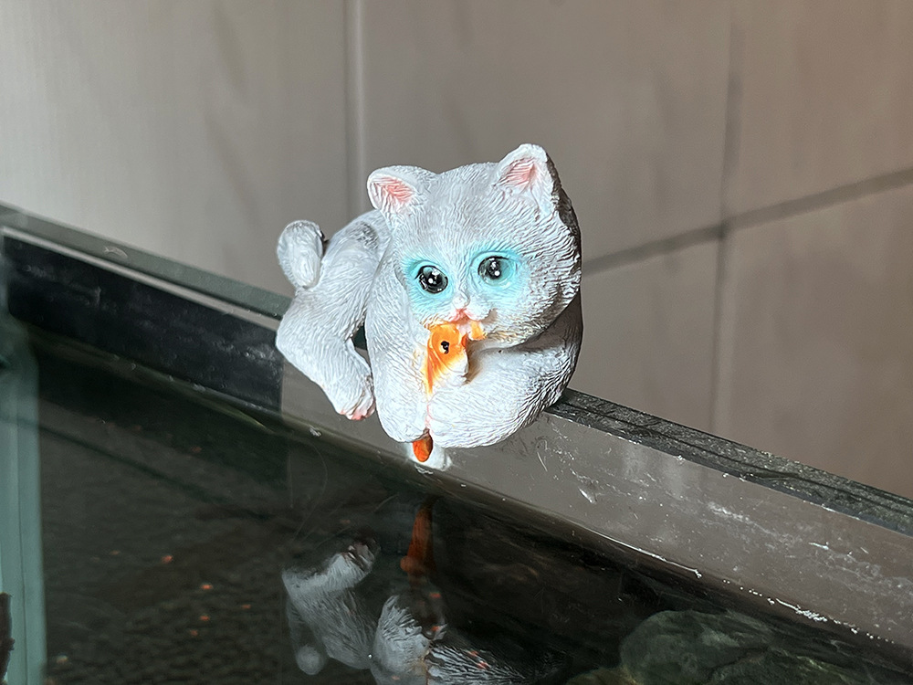 Котенок обнимает рыбу серого цвета