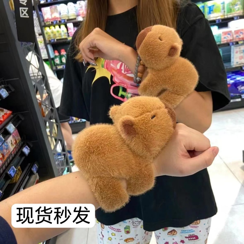 震える音の同じタイプのカピバラはパチパチと腹ばいになって腕のぬいぐるみを抱いています。|undefined