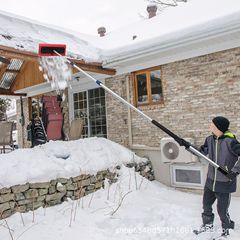冬の屋根の雪の神器は雪の板のの雪の熊手の上空の除雪の道具をかきます。