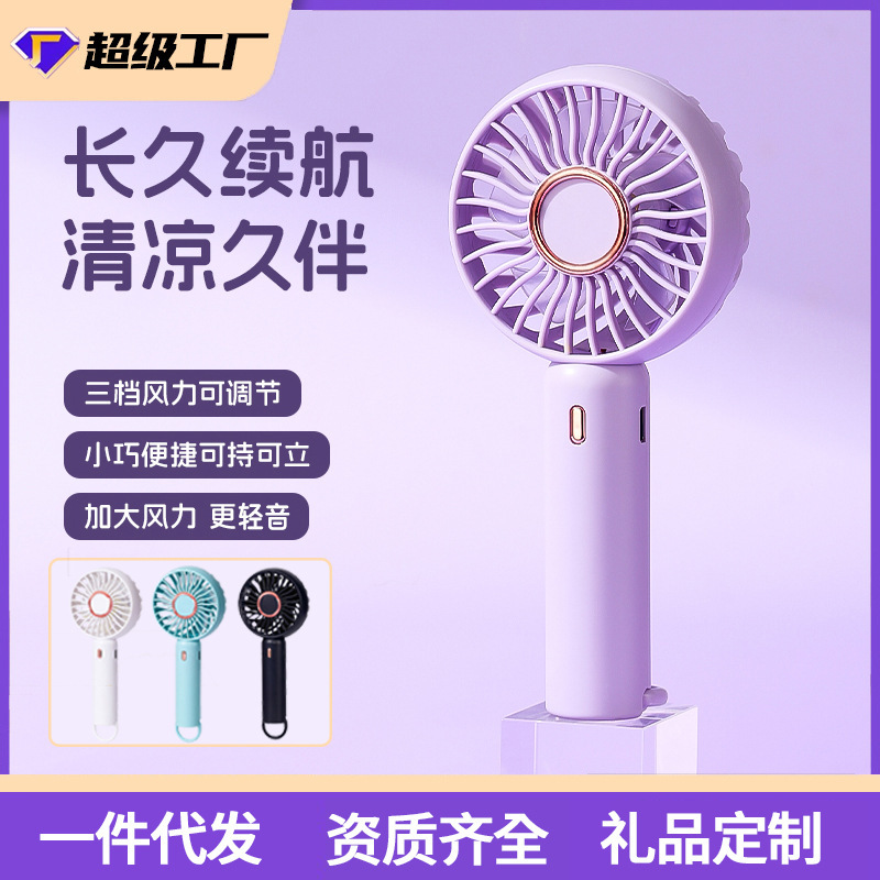 小型扇風機を持って小型充電式の学生がデスクトップを持っています。|undefined