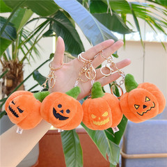 ハロウィーンのかぼちゃのキーホルダーのカバンはかわいいぬいぐるみの幽霊のリュックサックに飾られています。