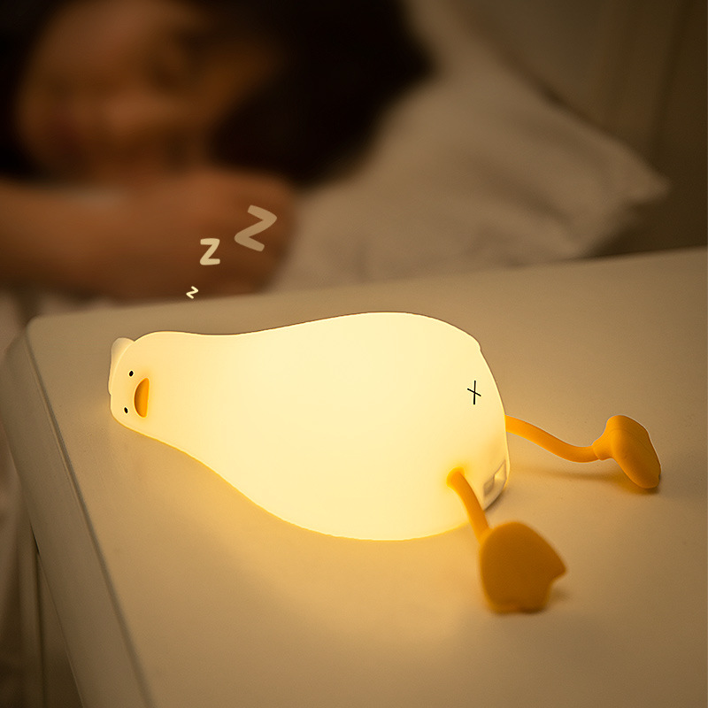 横になっているアヒルの小夜灯が明かりをたたいてシリコンledが寝返りを打ったアヒルの充電ベッドの頭に寝ている携帯電話スタンドの夜灯のアイデア