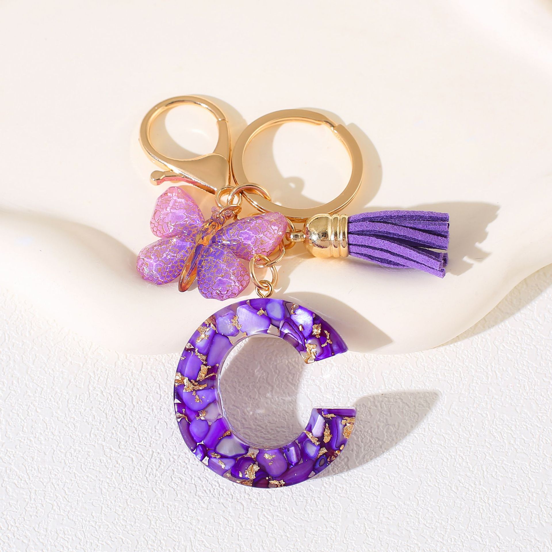 Fábrica directa de Yiwu accesorios de resina de goteo de embalaje llavero anillo de metal letras mariposa brilla colgante damas