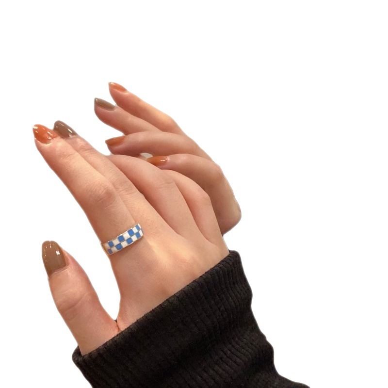 Un diseño de nicho con patrón de tablero de ajedrez en blanco y negro para blogueras de Instagram con el mismo anillo en el dedo índice._voghion.com