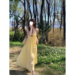 フランスの黄色のストラップのワンピースの婦人服の夏の海辺のリゾート風はスカートのゆったりしたa字のスカートの長いスカートに乗ります。