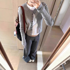 灰色の優しい風の甘い長袖の単列のニットのカーディガンの上着の女性の早春の修身はやせている短いタイプの上着を現します。