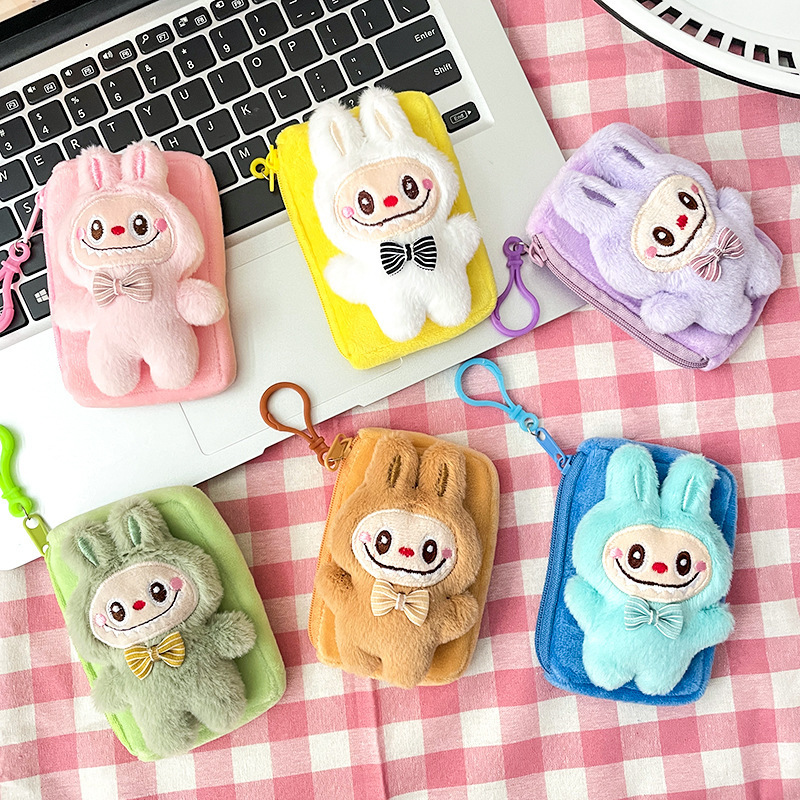 震え音の赤い本が爆発してかわいいぬいぐるみの布の小銭入れのキーホルダーのイヤホンのかばんにプレゼントを掛けます。|undefined