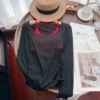 Чёрная плиссированная накидка, ярко‑красный топ на завязках