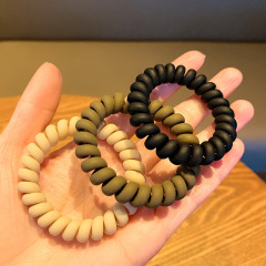 ミルク茶色の電話線の髪輪の少女の団子の頭の皮の筋は縄を刺します。
