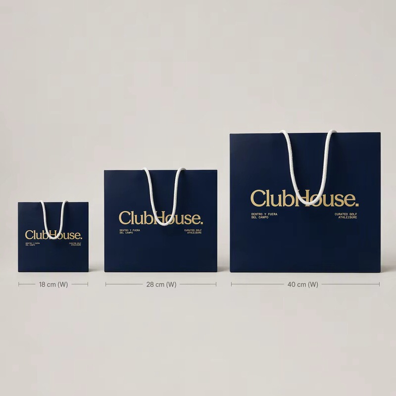 High-end custom gold foil embossed navy blue matte shopping bag, with white woven rope handles and logo