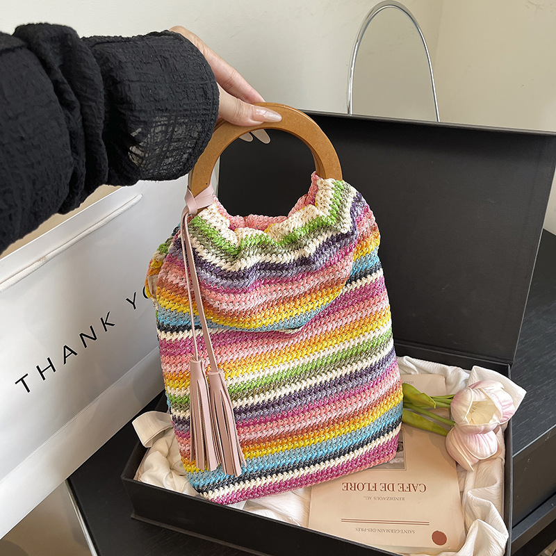 Versión coreana del bolso de cubo de nicho 2025 verano nuevo bolso femenino a rayas bolso de color en contraste bolso tejido con borlas de paja marea