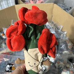 手に花の束の人形のぬいぐるみの趣味を持っておもちゃのバレンタインデーの女性の誕生日プレゼントのボニーウサギのぬいぐるみのペンギンをなだめます。