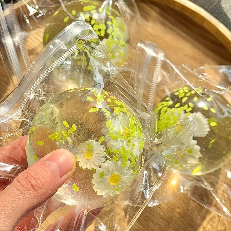 ネットの赤い爆発のココナッツの油の手はボールをつまんでゆっくりとボールをつまんで手でおもちゃの子供のプレゼントを解凍します。|undefined