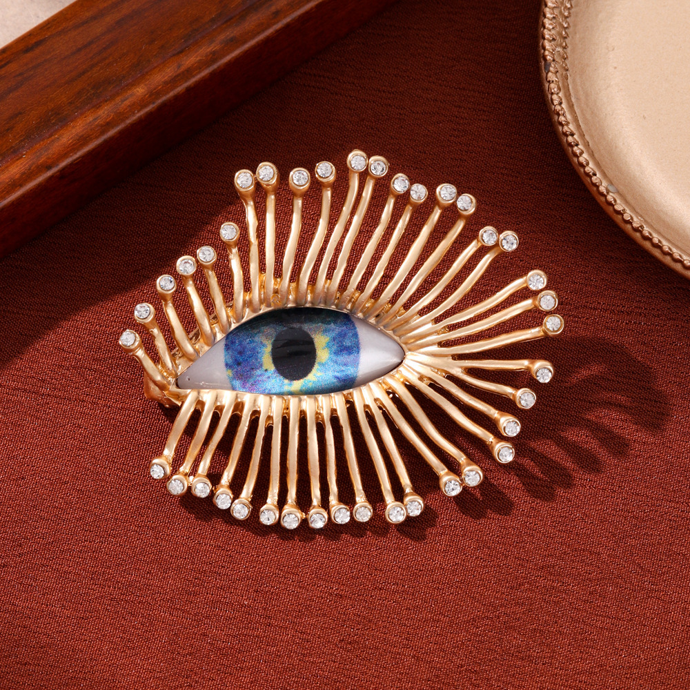 Broche vintage luxueuse et élégante haut de gamme, ornée de longs cils et d'un regard démoniaque, mettant en valeur une personnalité unique et exacerbée._voghion.com