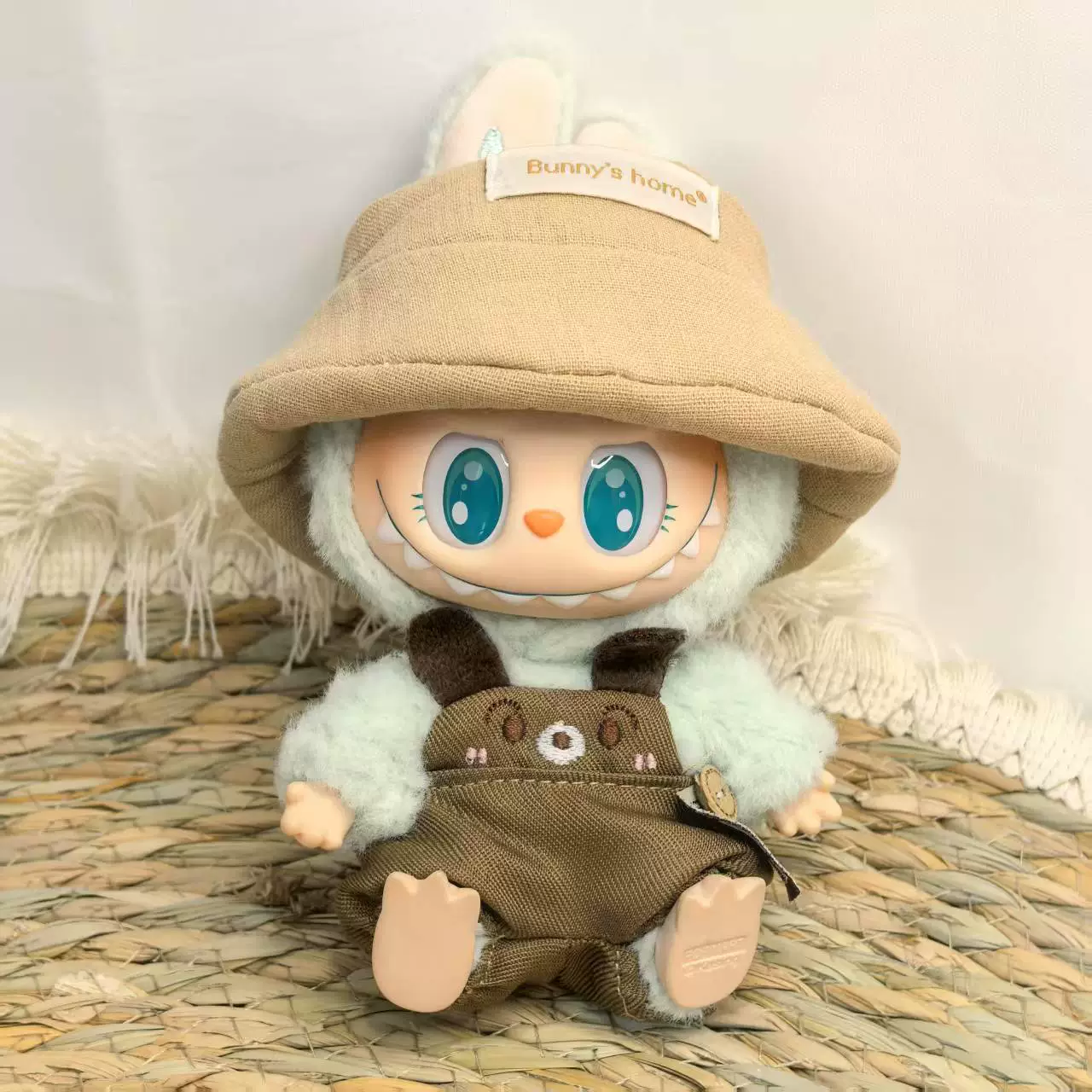 Лабубу Labubu сидит в джинсах, fisherman's шляпа, одет в милые простые детские наряды