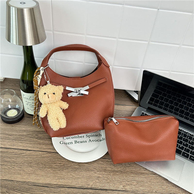 Un sentimiento de alto nivel de oso colgante bolso de cubo portátil para mujeres 2026 nuevo litchi nicho viaje mochila de hombro