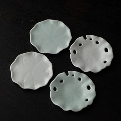 ハスの葉の陶磁器のコースターのお茶は脂の白い青磁の断熱のコップの台を支えます。