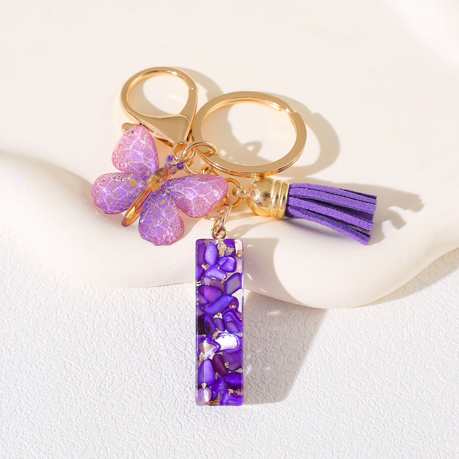 Fábrica directa de Yiwu accesorios de resina de goteo de embalaje llavero anillo de metal letras mariposa brilla colgante damas