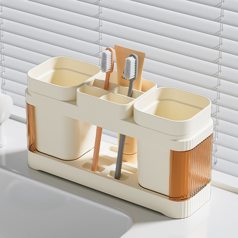 El baño de la Mesa de lavado de la pareja simple contiene un estante de taza de cepillo de dientes, un estante de taza de enjuague bucal de plástico, un estante de mesa de pasta de dientes.