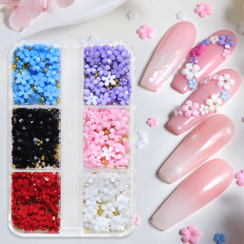 Decoraciones de uñas con flores de cinco pétalos en caja, decoraciones florales de resina de colores variados, accesorios de uñas con perlas y cuentas.
