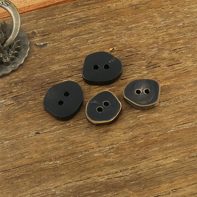 Natural genuine cow horn buttons, irregular two-hole buttons, matte black with burnt edges, for shirts, vests, and denim jackets Natural genuine cow horn buttons, irregular two-hole buttons, matte black with burnt edges, for shirts, vests, and denim jackets