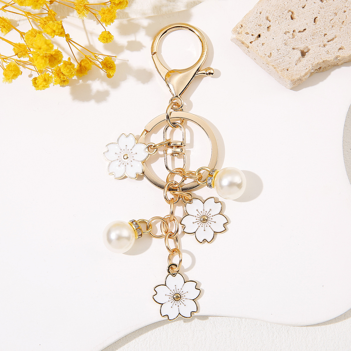 Venta al por mayor de llaveros de flores de cerezo japoneses que caen a mano, adornos de bolsos de mujer que gotean aceite, colgantes de perlas para parejas de novias