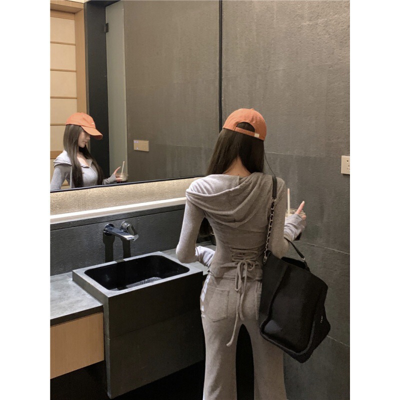 カジュアルスポーツスーツの女性は秋に帽子をかぶって腰のガードルのコートを着て、スピーカーでズボンを2セット持っています|undefined