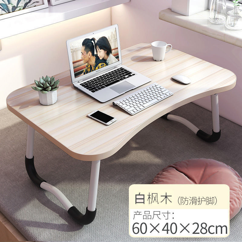 ベッドの上の机の折り畳みの小さい机は引き出しを持っています。|undefined