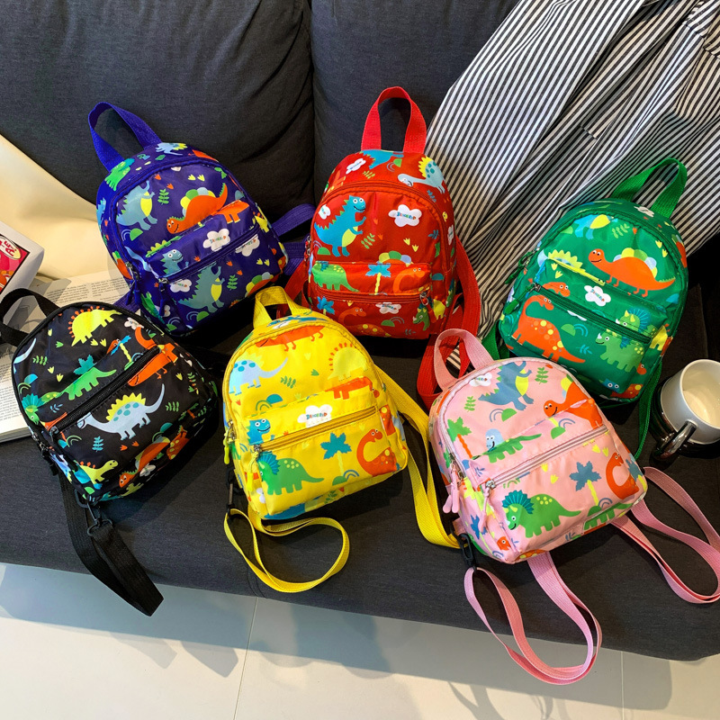 Mochila nueva al por mayor 2025, mochila de tela Oxford con diseño de dinosaurio de dibujos animados, mochila pequeña de gran capacidad para actividades al aire libre y ocio.