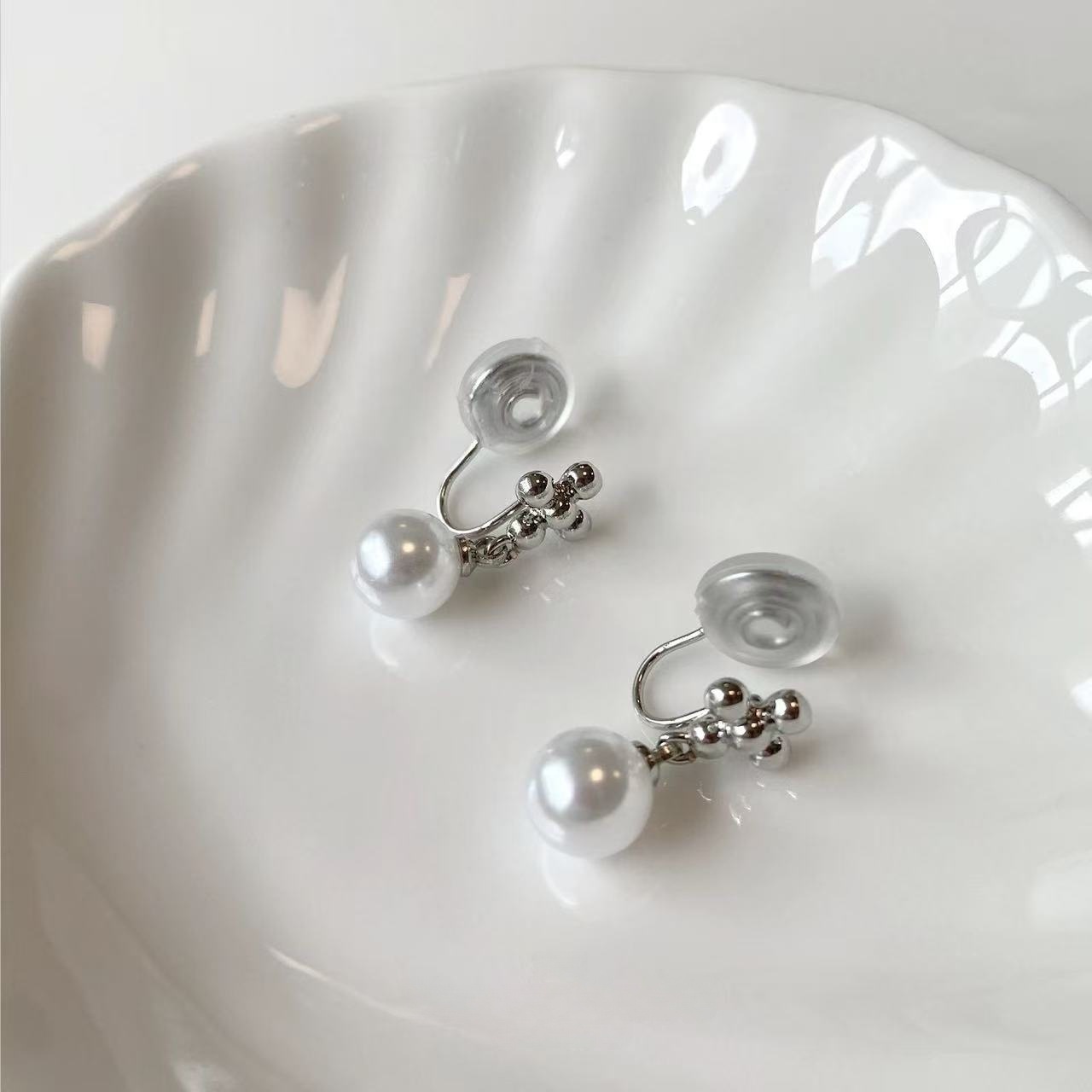 A pair of round pearl mosquito coil ear clips