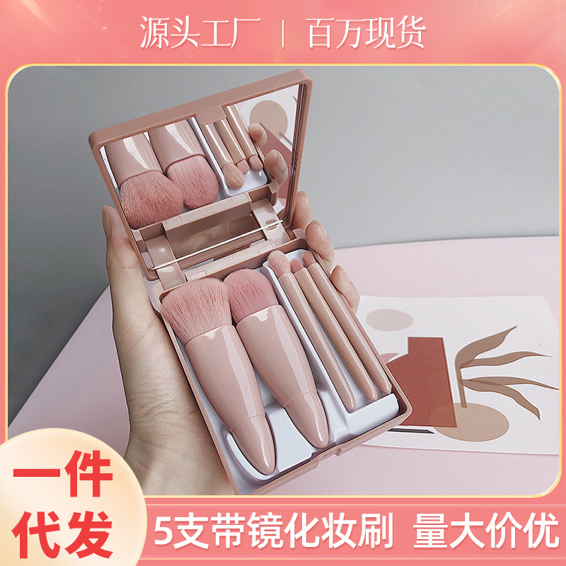 Un juego de 5 brochas de maquillaje portátiles en una caja con estuche con espejo, que incluye una brocha para base, una brocha para labios, una brocha para sombras de ojos, una brocha para polvos sueltos y un almacenamiento para productos de belleza.