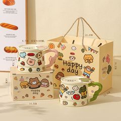 子供の趣味のかわいい落書きの陶磁器のマグカップは蓋の誕生日のプレゼントを持っています。