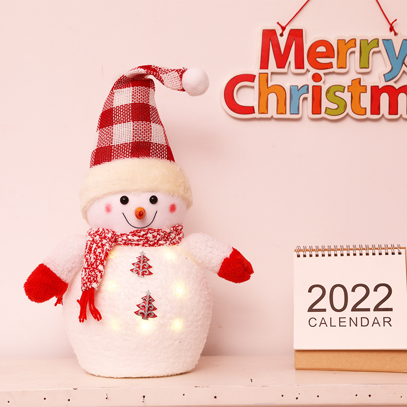 クリスマス発光雪だるま人形のデスクトップに子供の祝日のプレゼントを飾っています。|undefined