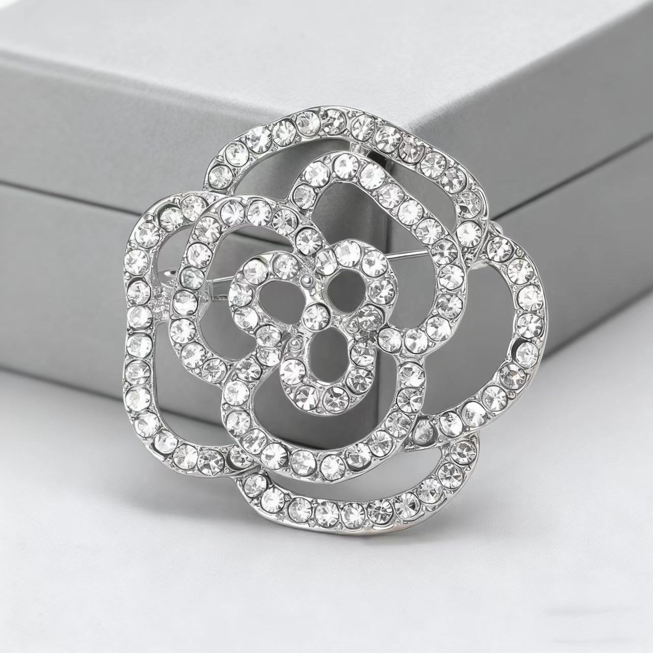 Elegant kameliabrosch med hålmönstrad rosdesign för rockar_voghion.com