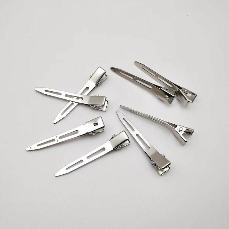 Studio makeup artist's hair styling tools: updo clips, shaping pins, beauty hairpins, duckbill clips, sectioning clips, positioning clips, and bang clips with pointed tips.