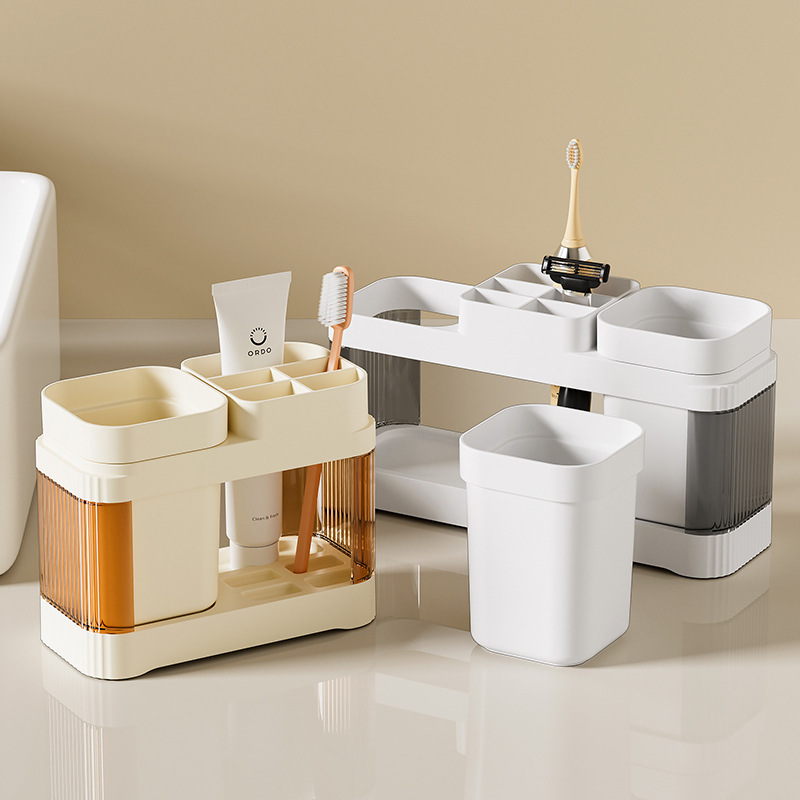 El baño de la Mesa de lavado de la pareja simple contiene un estante de taza de cepillo de dientes, un estante de taza de enjuague bucal de plástico, un estante de mesa de pasta de dientes.