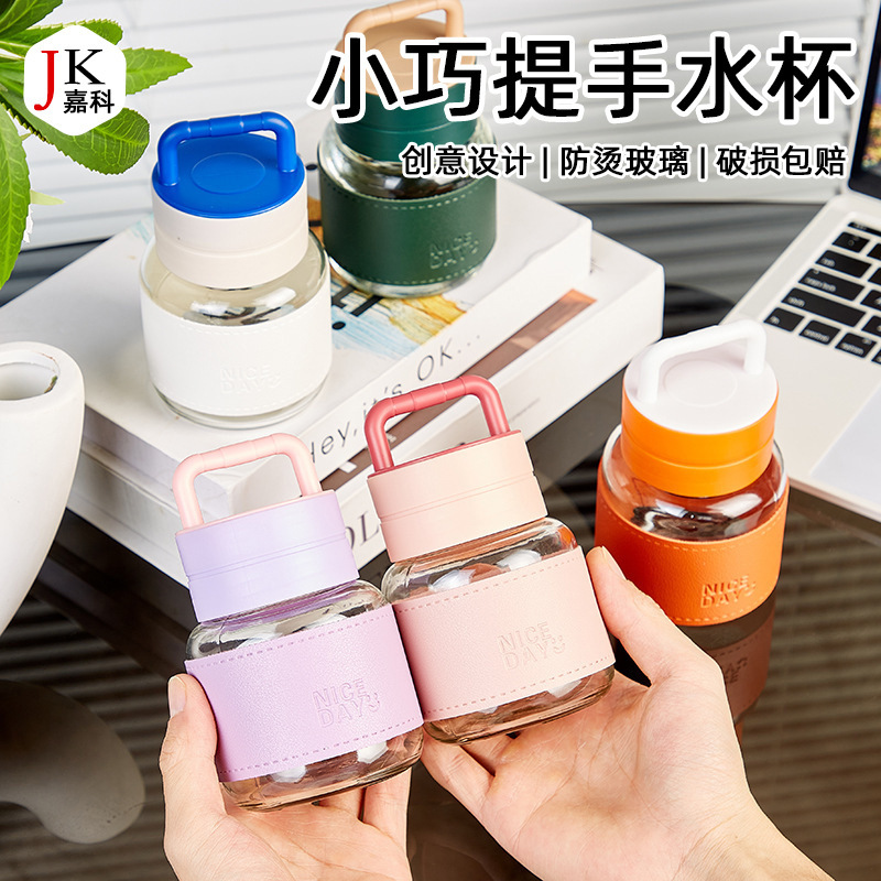手持ちの小さいコップのガラスの小さいミルクの杯はコップのジュースの杯を揺り動かします。|undefined