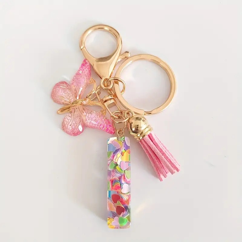 2024 transfronteriza en stock resina rosa con lentejuelas 26 letras inglesas llavero colgante mariposa borla Accesorios